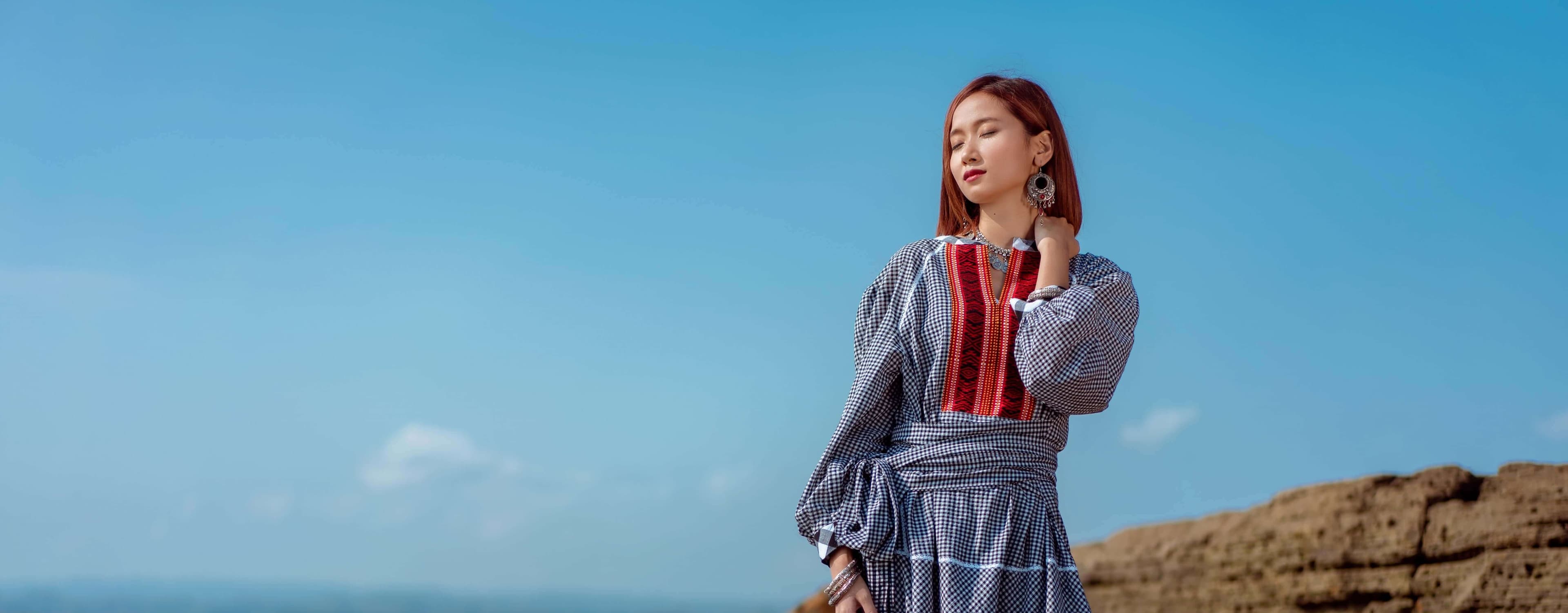 Model in traditional dress against a blue sky